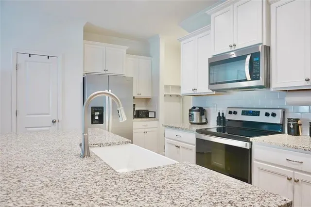 a kitchen with stainless steel appliances kitchen island granite countertop a stove a sink and a microwave