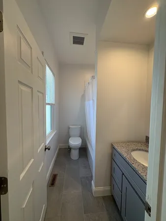 a bathroom with a granite countertop sink a toilet and a tub
