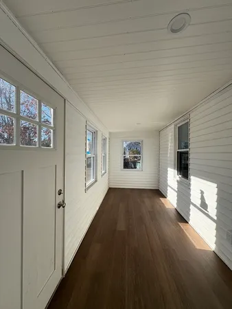 a view of a hallway with wooden floor and a living room