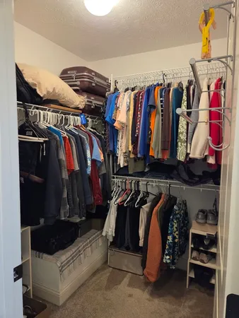 a view of walk in closet with clothes and shoes