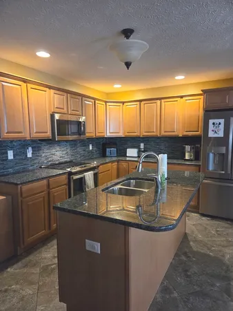 a kitchen with kitchen island granite countertop a sink window and cabinets