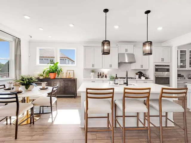 a kitchen with a dining table chairs and white cabinets