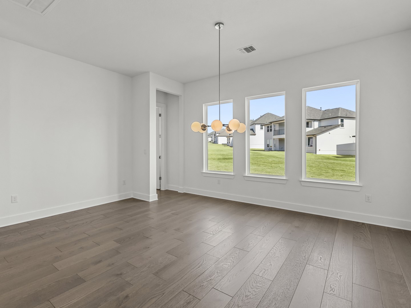 2508 Chiavari Way Leander, TX 78641 - Photo 2 of 24 Hardwood flooring extends throughout this versatile living area, illuminated by a modern light fixture.
