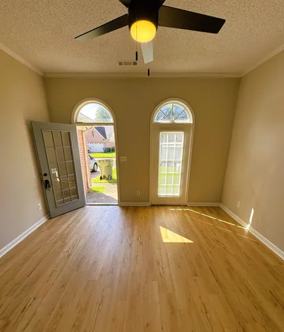 a view of empty room with wooden floor and fan