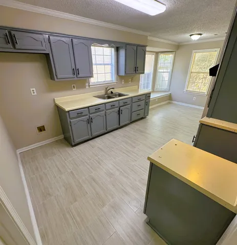 a kitchen with stainless steel appliances a stove a sink a refrigerator white cabinets and wooden floor