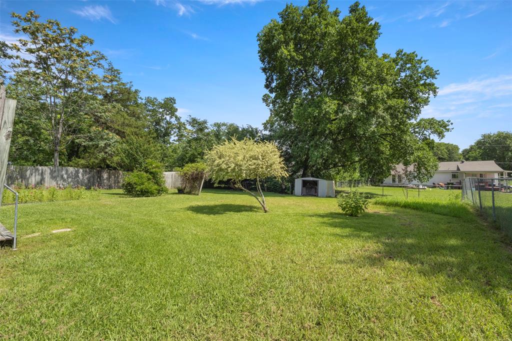 829 West 9th Street Bonham, TX 75418 - Photo 30 of 30 Expansive grass yard with mature trees, a small storage shed, and partial fencing