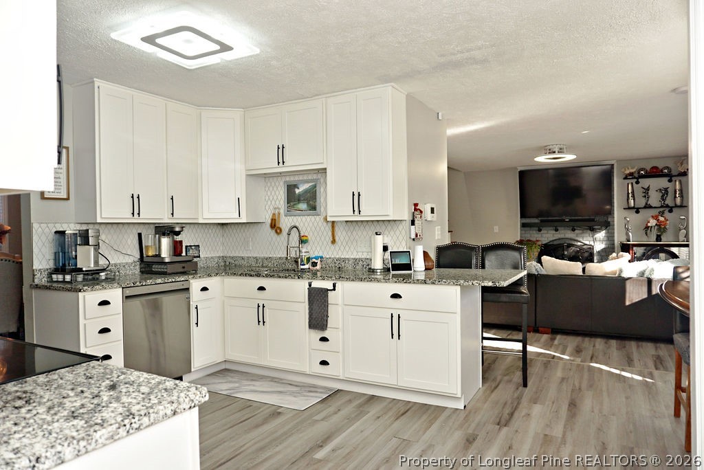 8363 King Road Fayetteville, NC 28306 - Photo 19 of 44 a kitchen with granite countertop a stove top oven a sink dishwasher and white cabinets with wooden floor