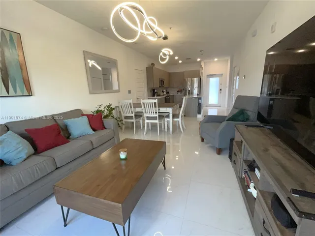 a living room with furniture a rug and kitchen view