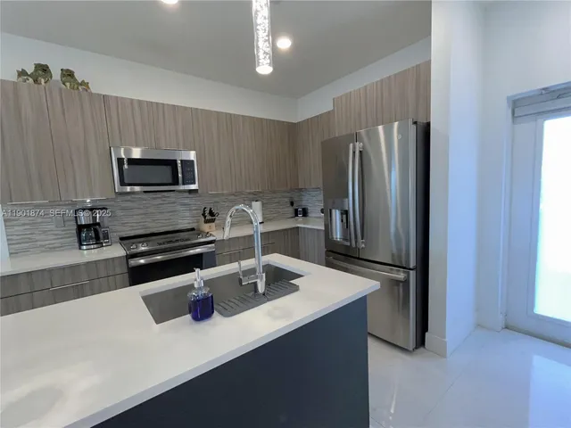 a kitchen with a refrigerator a microwave a sink and cabinets