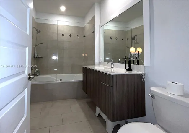 a bathroom with a bathtub shower sink vanity and toilet