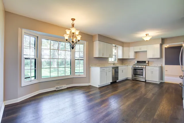 a kitchen with granite countertop white cabinets and wooden floor
