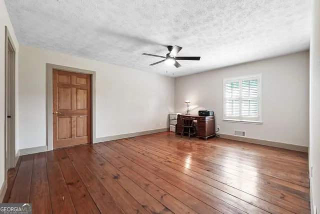 a view of empty room with wooden floor and ceiling fan