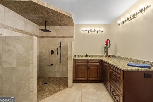 a bathroom with a granite countertop shower a sink and a mirror
