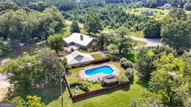 an aerial view of a house with swimming pool and large trees