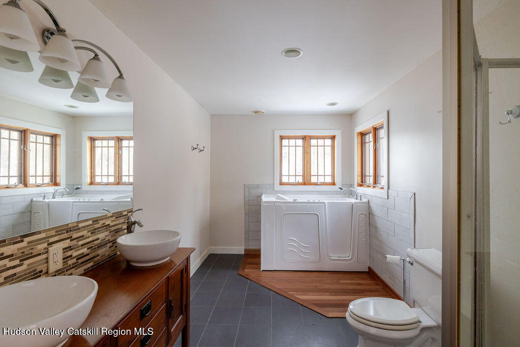 53 Snyder Pond Road Copake, NY 12516 - Photo 12 of 47 a bathroom with a granite countertop sink toilet a mirror and tub