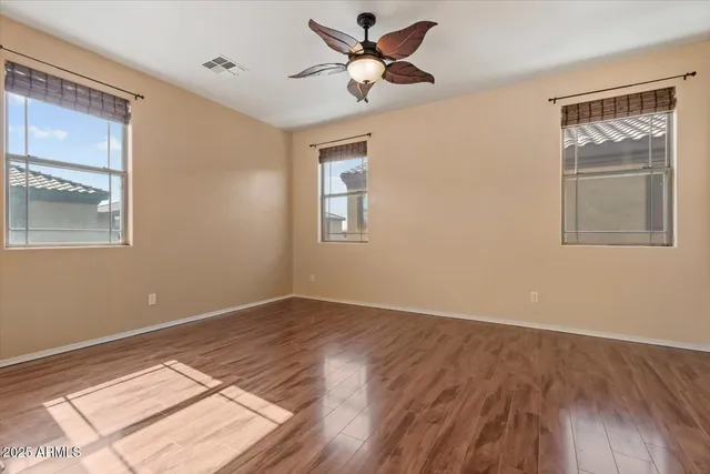 a view of an empty room with a window and wooden floor