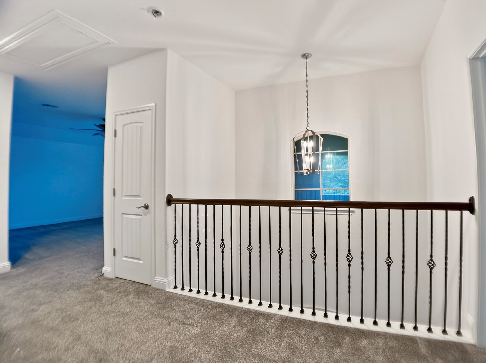 1505 Long Shadow Lane Georgetown, TX 78628 - Photo 19 of 28 Upper-level hallway featuring gray carpeting, a wrought iron and wood-finish railing, a white arched window, and a brushed nickel pendant light fixture