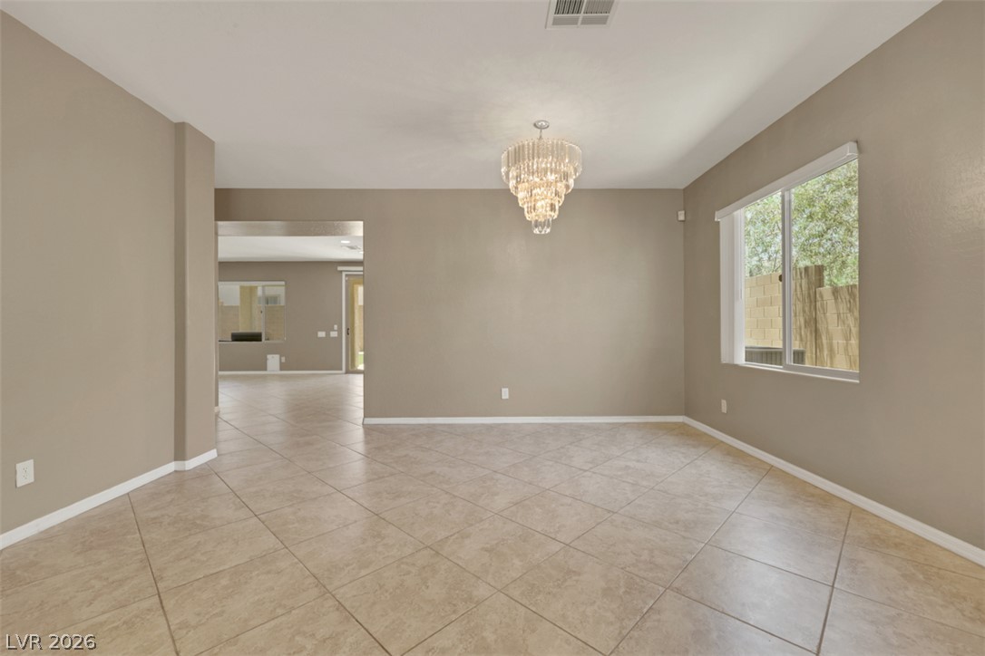 2501 Bechamel Place Henderson, NV 89044 - Photo 5 of 50 A shimmering chandelier illuminates this versatile space, featuring tiled floors and an exterior view through a large window.