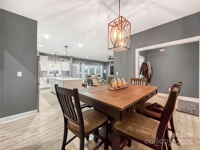 a view of a dining room and livingroom with furniture wooden floor a chandelier