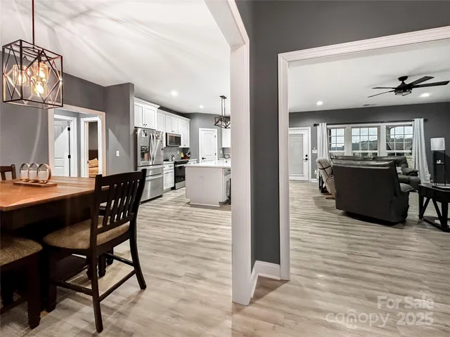 a view of a dining room and livingroom with furniture wooden floor a chandelier