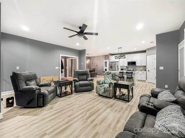 a living room with furniture kitchen view and a wooden floor