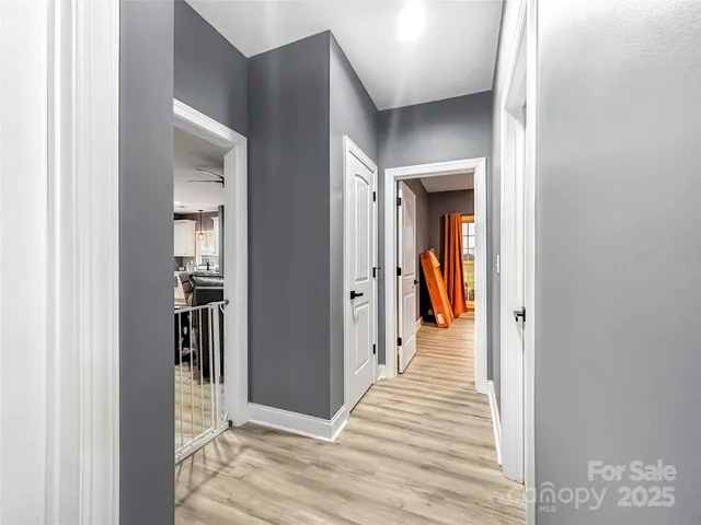a view of a hallway with wooden floor and a bathroom