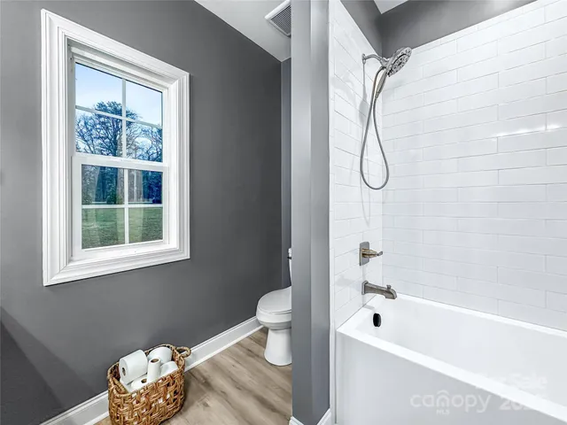 a bathroom with a bath tub a toilet and a window