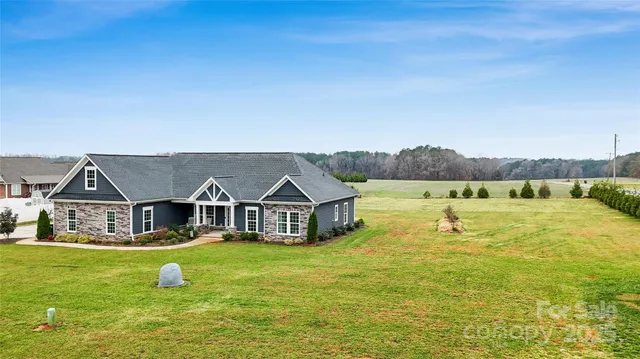 a view of a house with a big yard and large trees