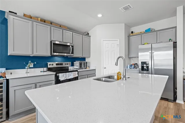 a kitchen with stainless steel appliances a stove a refrigerator a sink a stove with white cabinets