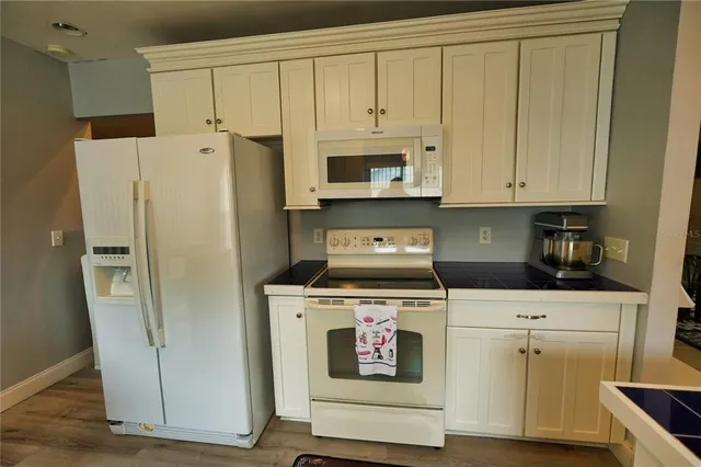 a kitchen with white cabinets and white appliances