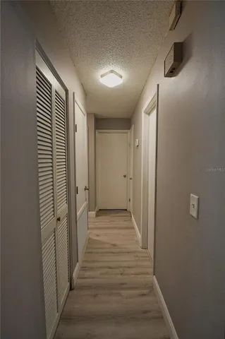a view of a hallway with wooden floor and closet area
