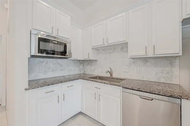 a kitchen with granite countertop white cabinets stainless steel appliances and a sink
