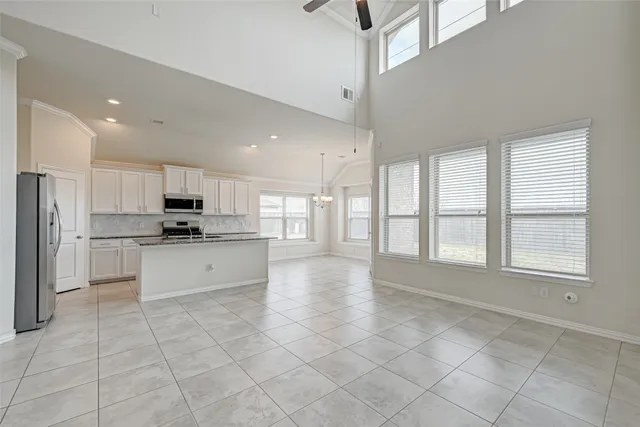 a kitchen with stainless steel appliances kitchen island granite countertop a refrigerator a sink and white cabinets