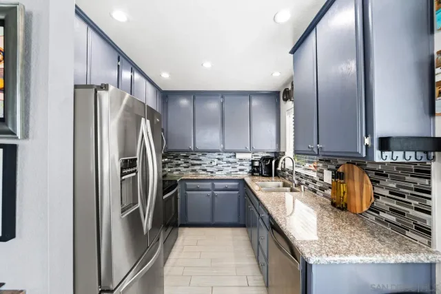 a kitchen with stainless steel appliances granite countertop a refrigerator a stove and a sink