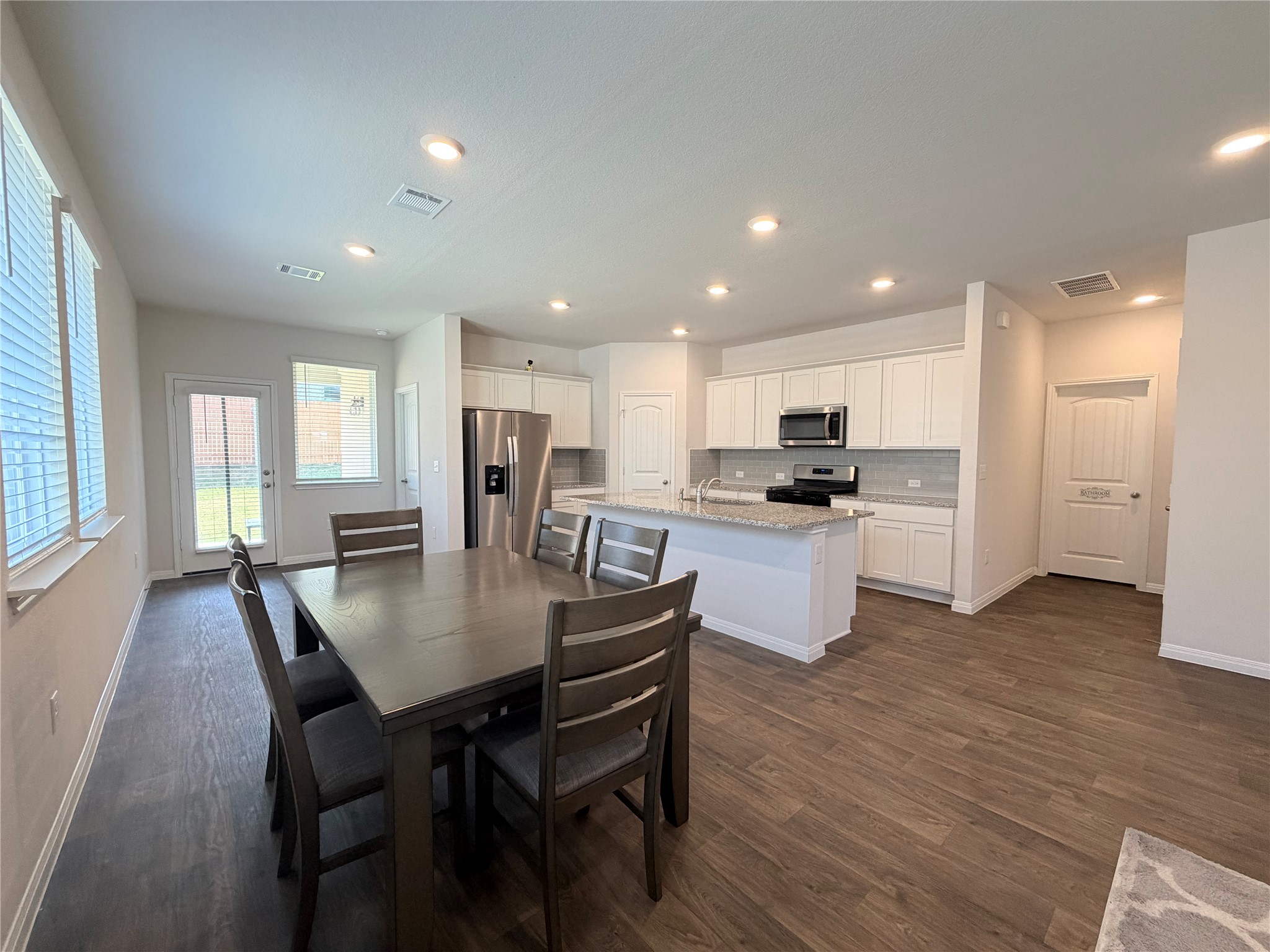 129 Saide Street Georgetown, TX 78626 - Photo 11 of 36 An open kitchen and dining area features recessed lighting, durable wood flooring, and granite countertops.