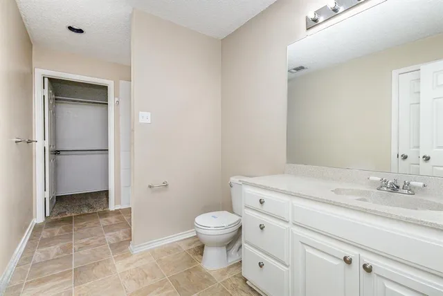a bathroom with a granite countertop sink a toilet and a mirror
