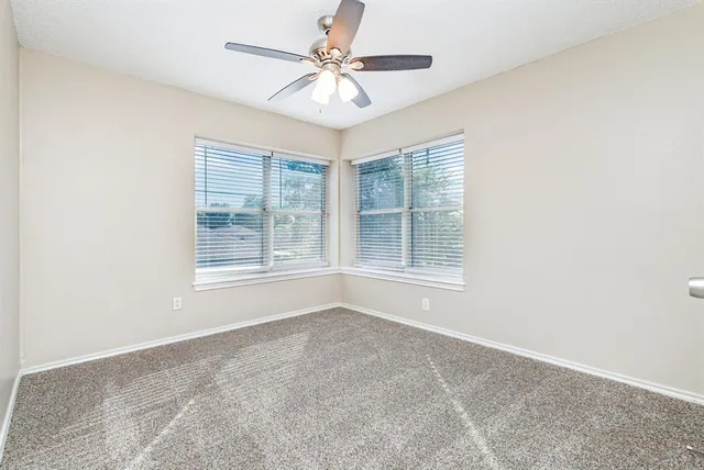 an empty room with windows and chandelier fan