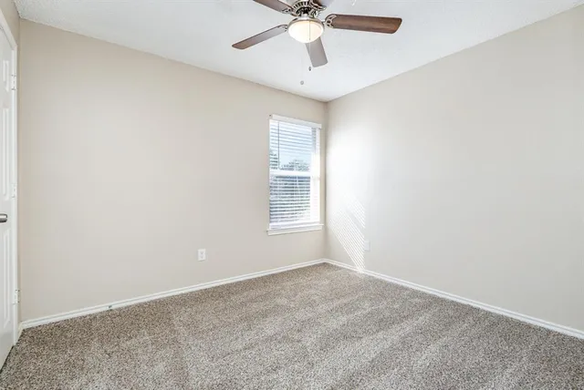 an empty room with a window and a fan