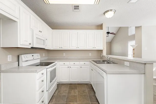 a kitchen with granite countertop white cabinets and white appliances