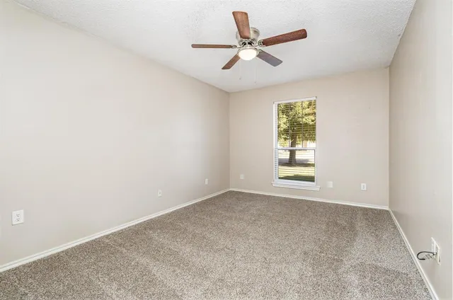 an empty room with a window and a fan