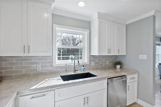a kitchen with stainless steel appliances granite countertop white cabinets sink and window