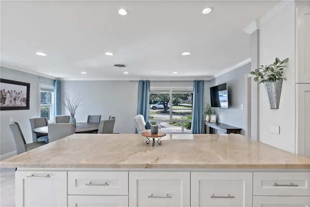 a dining hall with stainless steel appliances granite countertop a sink dishwasher and a dining table with wooden floor