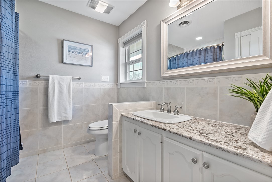 507 Crescent Drive Bryan, TX 77801 - Photo 30 of 41 a bathroom with a granite countertop sink a toilet and a mirror