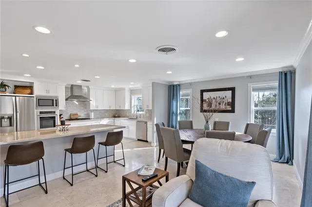 a living room with stainless steel appliances furniture a rug and a kitchen view