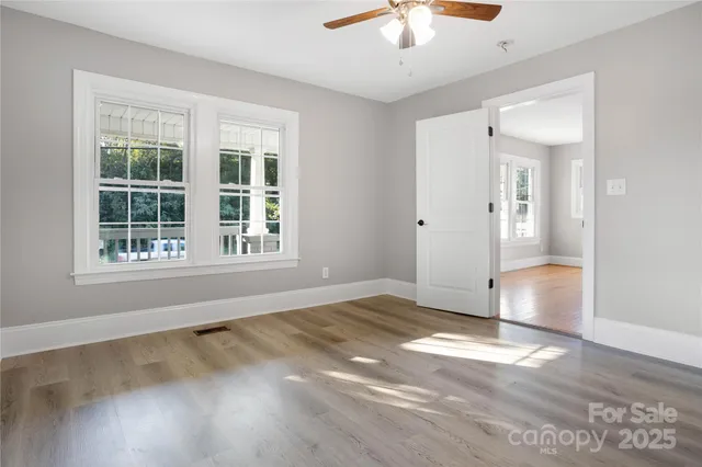a view of an empty room with a window and wooden floor