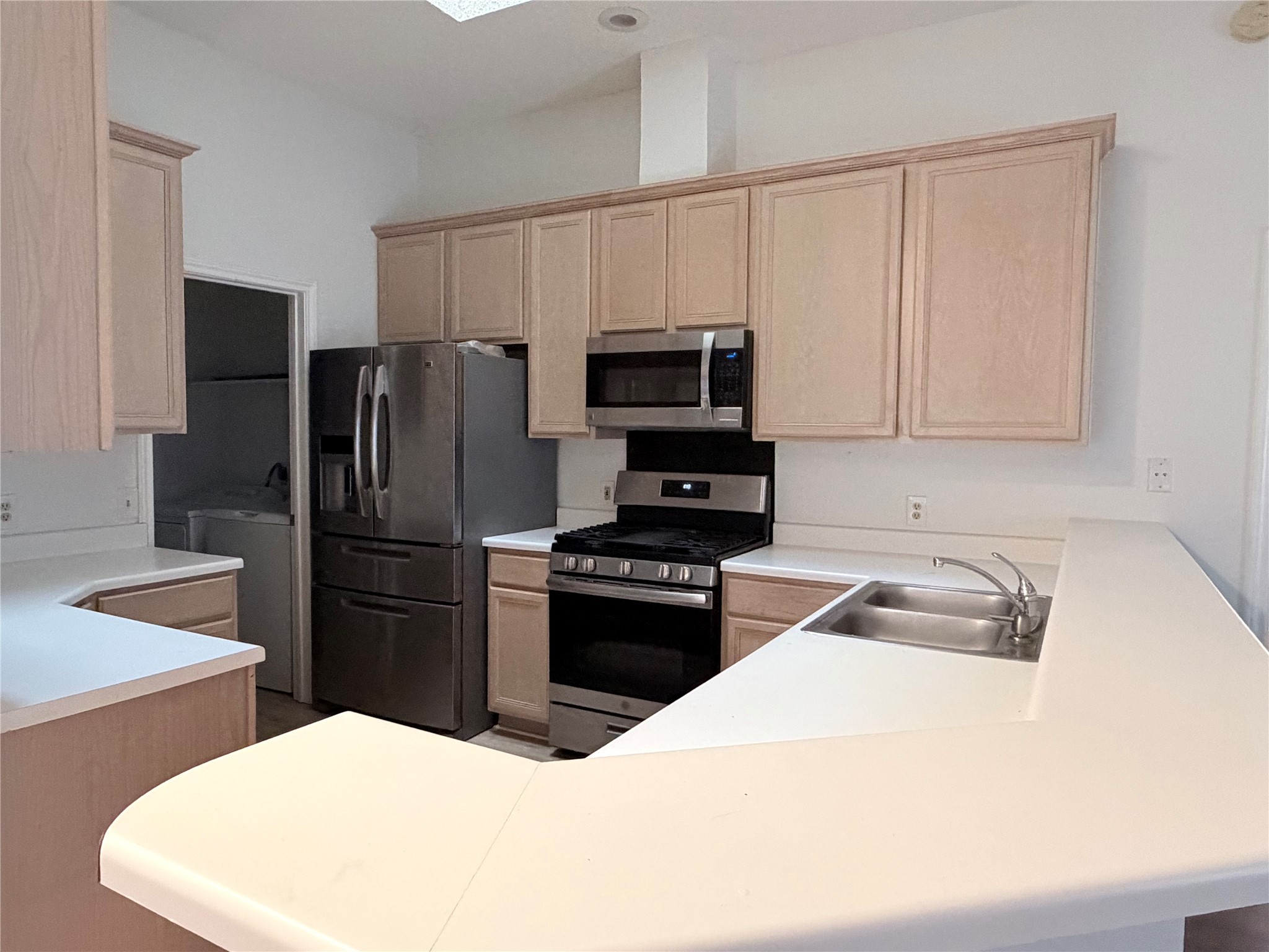 20809 Pacers Gait Lane Pflugerville, TX 78660 - Photo 8 of 23 Kitchen featuring a peninsula, stainless steel appliances, light countertops, and light wood finish cabinetry