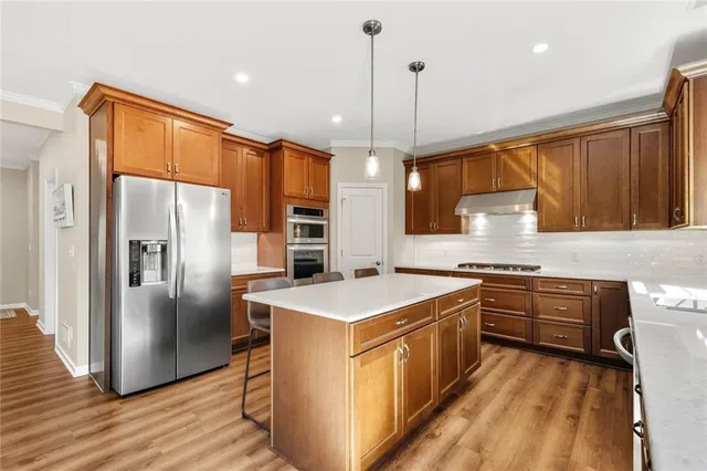 a kitchen with stainless steel appliances granite countertop a refrigerator a sink a stove and a refrigerator