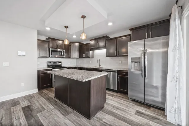 a kitchen with stainless steel appliances granite countertop a refrigerator a sink a stove a microwave and island