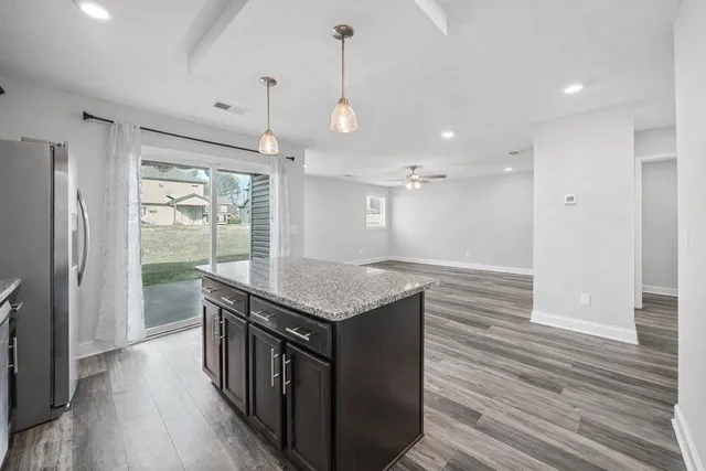 a kitchen with stainless steel appliances granite countertop a kitchen island a stove and a wooden floors