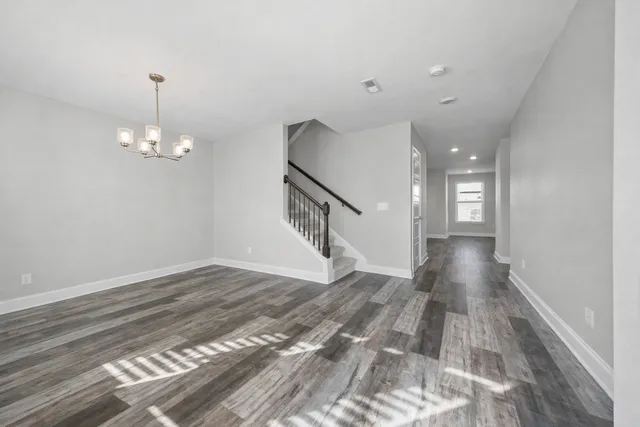 a view of an empty room with wooden floor and staircase